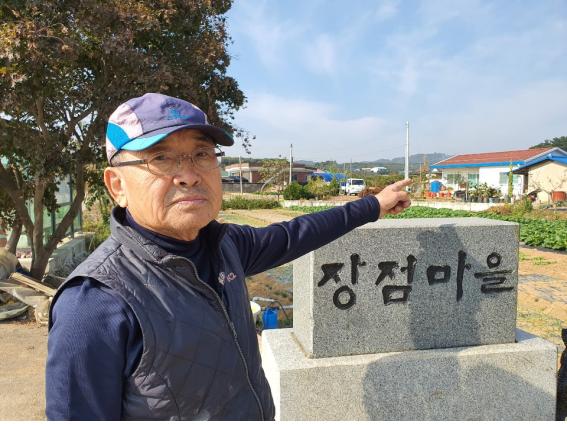 장점마을 입구에서 만난 문병준 씨. 원망스러운 마을 뒷산 비료공장을 가르키고 있다.