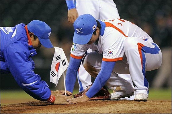 한국 승리의 주역 이진영 선수가(오른쪽) 마운드에 태극기를 꽂고 있다.