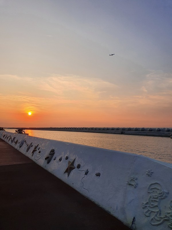 석양의 노을을 가르며 날으는 비행기 모습.