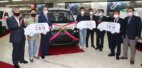 지난해 6월 24일 ㈜명신 군산공장에서 열린 군산형 일자리 생산 1호차인 다니고 VAN 출고식 행사에서 송하진 도지사, 이태규 (주)명신 대표, 강임준 군산시장 등이 1~3호 차량 지역사회 기승식 을 갖고 기념촬영을 하고 있다.(사진=전북도 제공)