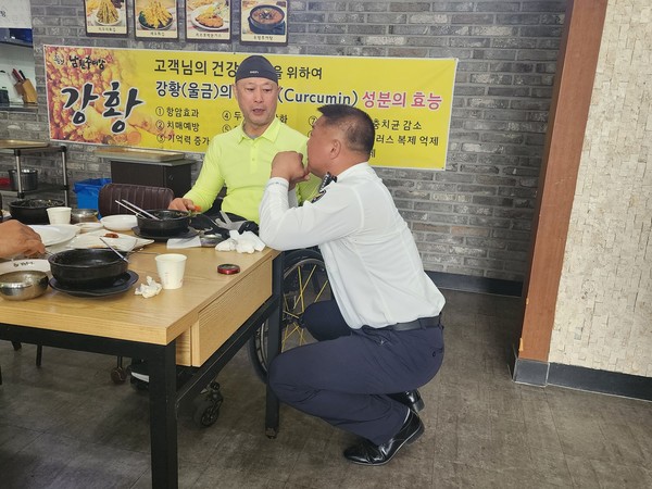 손으로 국토종단 팀의 리더인 김준형 센터장과 자세를 낮추고 대화를 나누는 추원호 용인 동부경찰서 교통안전계장의 모습.