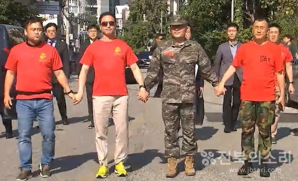 1일 오전 국방부 중앙지역군사법원 앞에서 빨간색 해병대 티셔츠를 입은 박정훈 대령의 예비역 해병대 사관(해간) 81기 동기들이 시민 1만 7,000명이 서명한 구속 기각 탄원서를 전달한 뒤 박 전 대령과 함께 손을 잡고 있다. 이들 동기는 해병대 군가 ‘팔각모 사나이’를 합창하며 박 대령을 응원해 시선을 끌었다.(사진=예비역 해간 출신 제공) 